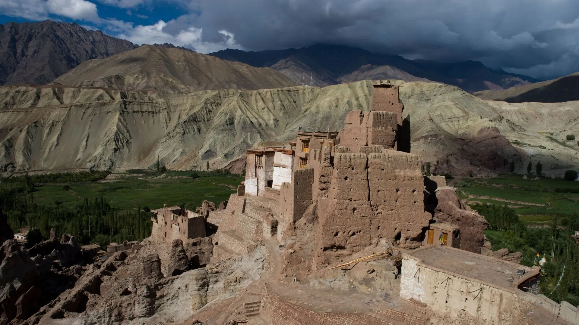 Majestic ruins of Basgo Fort perched on a rocky hill, panoramic view of the surrounding valley from Basgo Fort, solo traveler exploring the ancient architecture of Basgo, group of travelers taking photos of the crumbling walls of Basgo Fort, vibrant murals inside the fort reflecting its rich history, dramatic landscape surrounding Basgo with mountains in the background, solo traveler contemplating the history of Basgo Fort, group of friends hiking to the top of Basgo for stunning views, remnants of ancient structures nestled in the hills of Basgo, sunset casting a warm glow over the fort ruins.