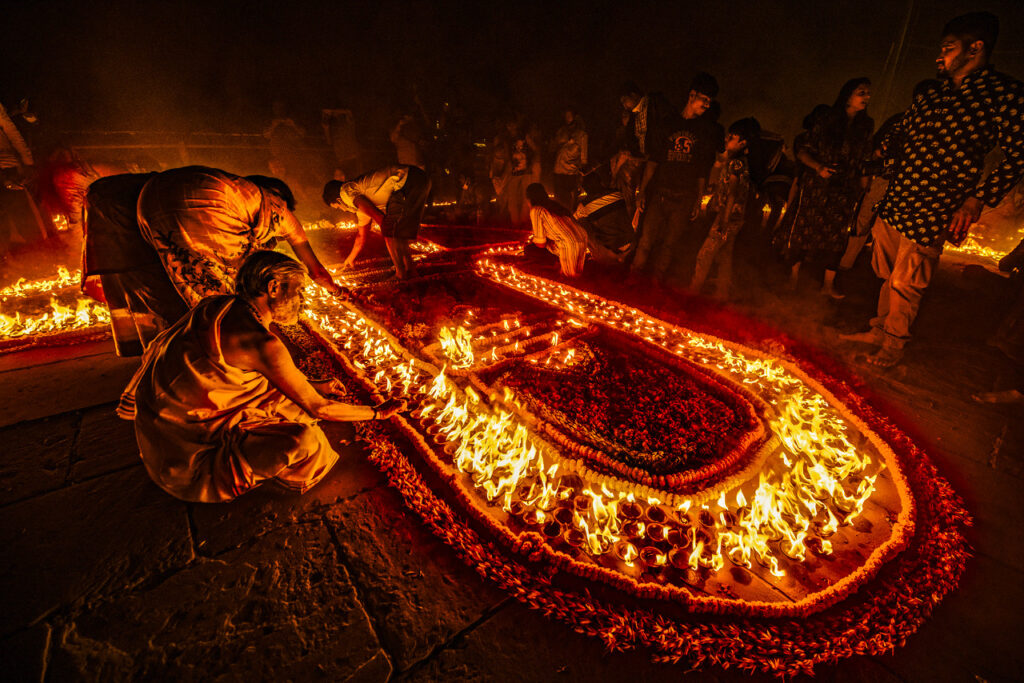  During Dev Diwali in Varanasi, the skies above the Ganges come alive with vibrant fireworks, offering a stunning contrast to the serene spirituality of the festival, As night falls, the colorful explosions of light reflect on the river's surface, creating an ethereal scene that merges the tranquility of the water with the energy of celebration, This spectacular display symbolizes the fusion of devotion and joy, with locals and visitors gathering on boats and along the ghats, cheering as the sky is filled with brilliant hues, The event fosters a sense of togetherness, where reverence and celebration coexist, capturing the essence of life and light, The fireworks, combined with the lamps on the river, create a unique and unforgettable visual feast that adds a modern touch to the ancient rituals of Varanasi, showcasing the city's rich cultural diversity