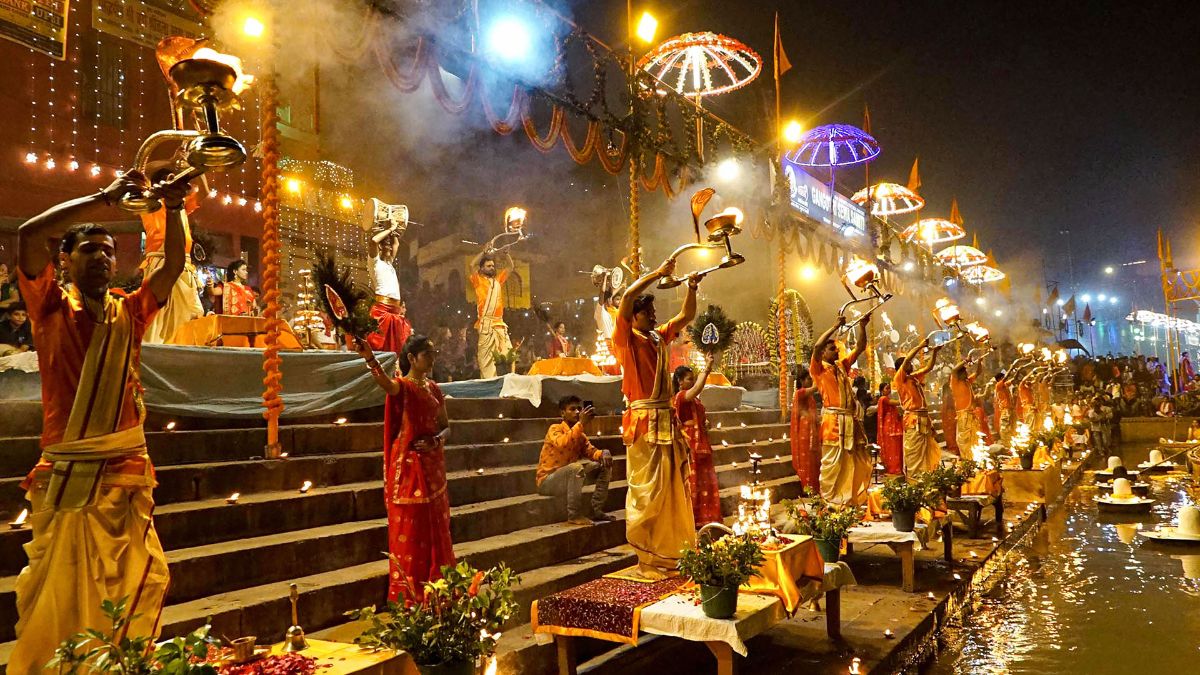  The Ganga Aarti in Varanasi is a profound spiritual experience, reaching new heights of grandeur during Dev Diwali, As the sun sets, priests in traditional attire gather at the ghats with large brass lamps, incense, and flowers, filling the air with the sounds of conch shells, bells, and sacred chants, Each synchronized movement of the ritual holds deep symbolic meaning, honoring the river Ganga as a divine source of life and purification, During Dev Diwali, the aarti becomes even more elaborate, with larger-than-life lamps and powerful chants resonating across the riverbanks, creating an almost otherworldly atmosphere, The gathering of hundreds adds to the awe of the ceremony, making it a deeply meditative experience, Witnessing the aarti connects participants with the ancient traditions of the city and the sanctity of the river, evoking a sense of unity with the divine, The ritual serves as a reminder of humanity’s spiritual bond with nature, leaving a lasting impression on all who are fortunate enough to experience it,